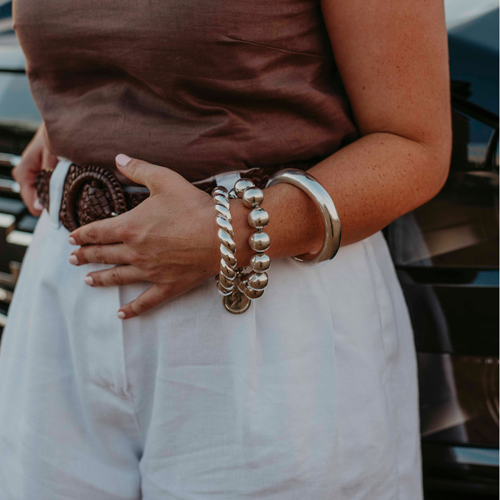 Lucy - Signature Sterling Silver Lucy wearing a 925 Chunky Sterling Silver twisted golf bangle, 925 Sterling Silver ball bracelet in 18mm balls with sterling silver coin pendant, and 925 Sterling Silver plain chunky golf bangle.